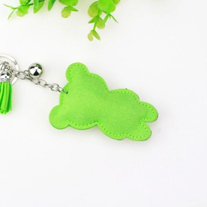 Close-up of a green suede bear keychain with a matching tassel and silver bell detail