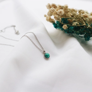Detailed macro view of S925 silver turquoise pendant necklace on white fabric