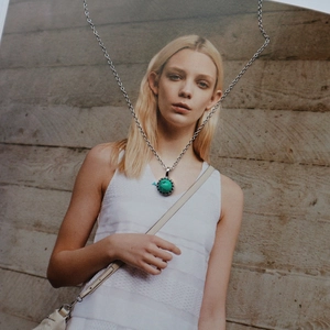 Detail of s925 sterling silver turquoise pendant necklace with vintage edge on a magazine