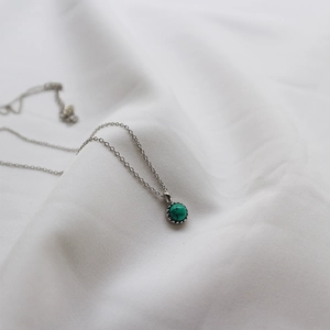 Close-up of S925 silver turquoise necklace lying on soft white draped fabric