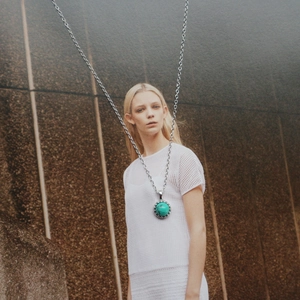 Detail of s925 silver necklace with turquoise pendant shown on a model neck