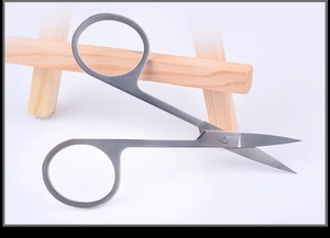 Detailed view of stainless steel beauty scissors with sharp tips on wooden stand