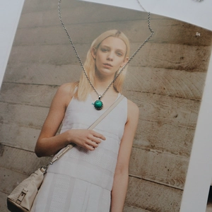 Detail of silver chain with turquoise pendant placed on artistic portrait background