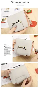 Detail of grey cat-ear metal buckle and tassel on small faux leather wallet