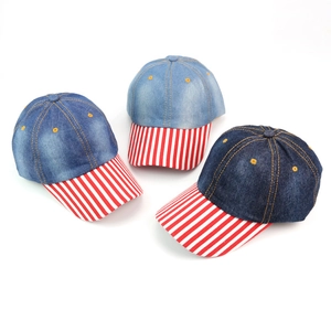 Close-up of three denim baseball caps with vintage washes and red striped brims