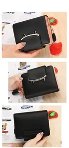 Detail of short black wallet with cute cat-ear metal buckle and leather tassel detail
