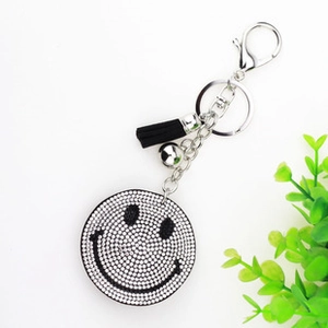 Close-up of black rhinestone smiley face keychain with black tassel and silver bell