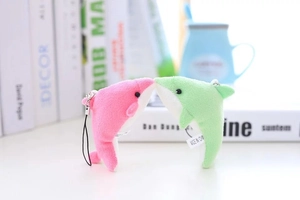 Gros plan de pendentifs dauphins en peluche rose et vert avec cordons sur table