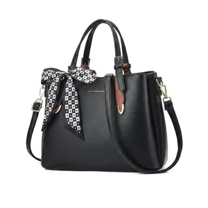 Detail of black lychee leather handbag featuring a checkered scarf handle and gold lettering