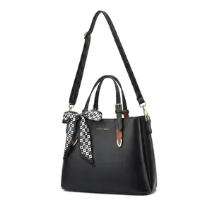 Detail of black lychee grain leather handbag with gold hardware and silk handle scarf