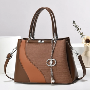 Detail of a brown woven pattern handbag with silver interlocking ring charm and wave stitching
