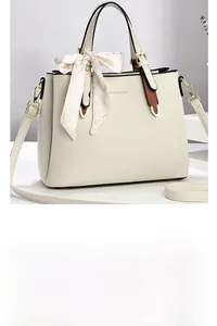 Detail of cream leather shoulder bag with floral scarf decor and gold metal buckle
