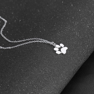 Macro shot of silver animal paw pendant with white enamel on a sleek alloy chain
