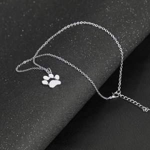 Macro view of a silver paw print pendant and polished alloy chain on black background