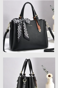 Detail view of black lychee leather tote bag with heart scarf and golden hardware