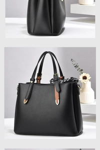 Close-up of black lychee leather handbag with brown straps and geometric silk scarf detail