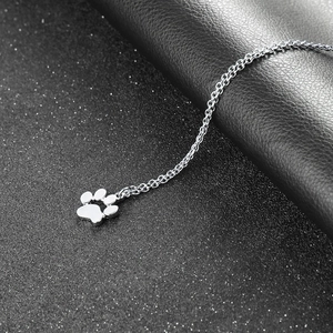 Detailed view of silver cat paw pendant with delicate chain on dark textured background