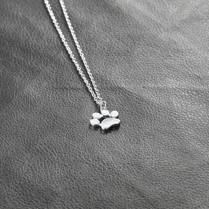 Macro shot of silver alloy animal paw print pendant with polished metal chain link
