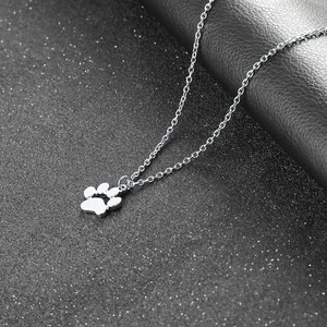 Detailed view of silver cat paw pendant with delicate alloy chain on dark textured surface
