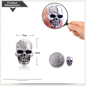 Detail of skull earring with white crystals, size 9mm by 16mm next to a coin
