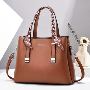 Brown leather handbag with fashion lettering and decorative scarf on the handle