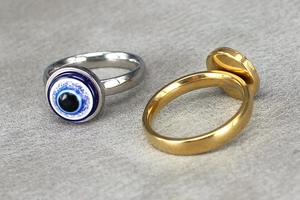 Close-up of gold and silver evil eye rings showing detailed enamel charms and polished bands