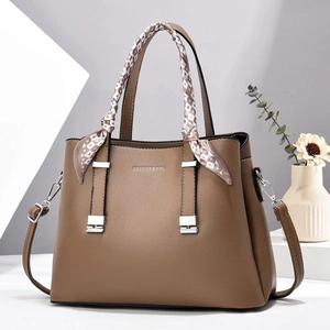 Detail of brown litchi pattern leather tote bag with silk scarf and fashion logo