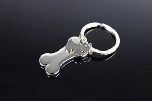 Close-up of polished silver metal dog bone and puppy charms on a keychain accessory