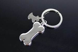 Polished silver metal keychain with bone and Scottish Terrier charms on a dark surface