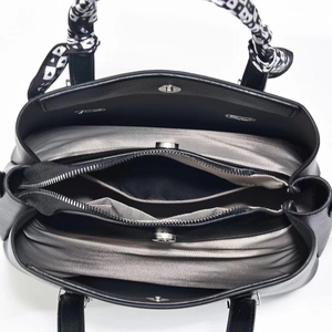 Detailed top view of the three interior compartments and zipper pocket of this black handbag
