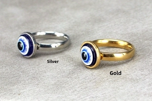 Close-up of gold and silver Evil Eye rings with polished finish and blue enamel eyes