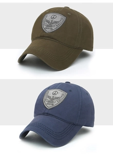 Detail of embroidered shield patches on olive green and navy cotton baseball caps