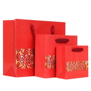 Set of red folk-style paper gift bags with traditional patterns and rope handles
