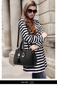 Detail of black lychee grain tote bag with gold teardrop lock and tassel charm