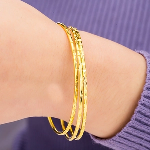 Three-piece set of golden Bohemian thin bangles featuring polished and textured finishes