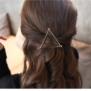 Detailed view of a golden triangular metal hair clip worn elegantly on blonde hair