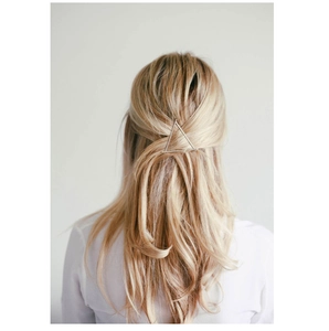 Minimalist silver triangle hair clip accessory shown on light blonde hair detail