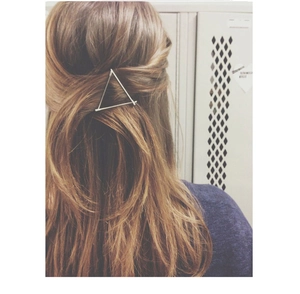 Detail view of a triangular metal hair clip worn on a half-up hairstyle