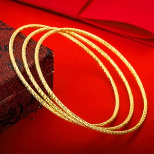 Three-piece gold-tone rope textured bangle set displayed on a red jewelry gift box