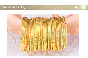 Detail of gold-plated stacked bangles with hammered and twisted textures on lace fabric