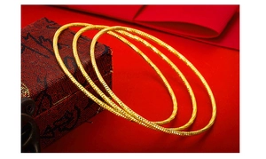 Detailed macro shot of three gold textured bangles on a vintage red jewelry box background
