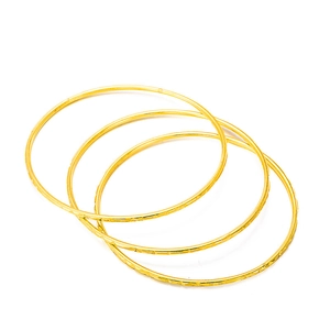 Three gold-plated bohemian bangles with geometric engravings on a white background