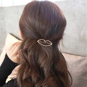 Lip-shaped golden metal hair clip accessory for women shown on brown wavy hair