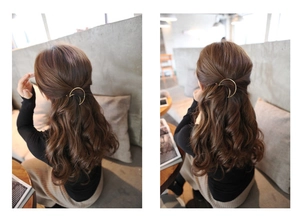 Golden crescent moon metal hair clip styled on long wavy brown hair for a chic look