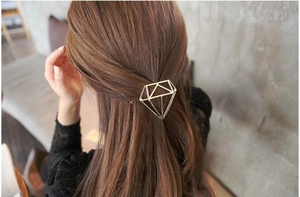 Macro shot of a minimalist golden hollow diamond-shaped geometric metal hair clip