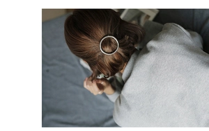 Silver circular metal hair clip shown worn on hair from a professional overhead angle