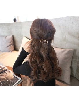 Detail view of a golden lip-shaped metal hair clip styled on a woman's hair