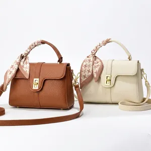 Detail of lychee textured leather handbags with silk scarf handle and gold twist lock