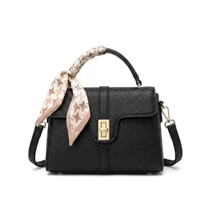 Detail of black lychee grain leather handbag with gold metal lock and silk scarf