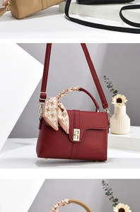 Detail of red litchi texture leather handbag with gold lock and houndstooth scarf handle